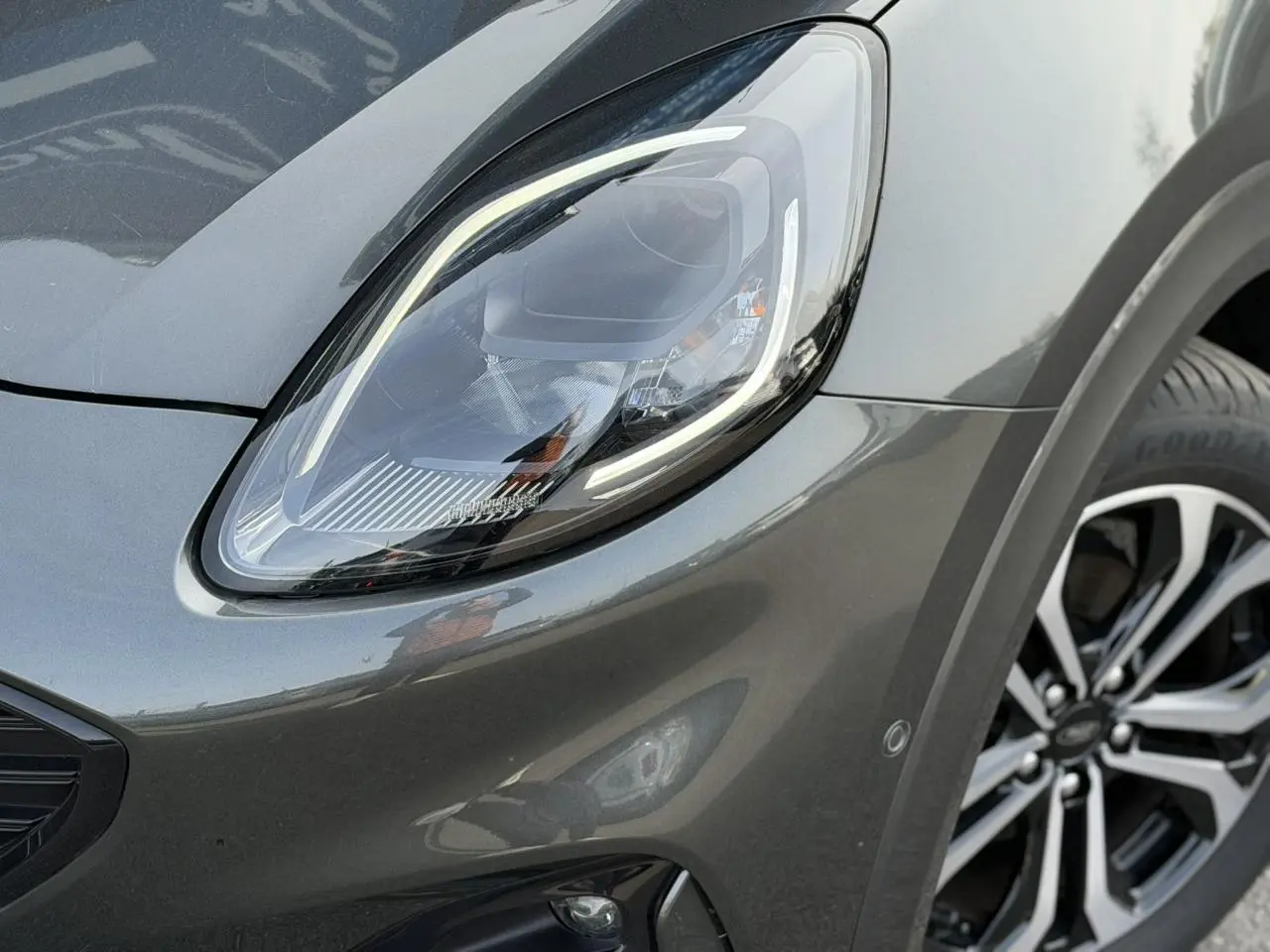 Gros plan sur le phare avant gauche et la roue alliage 17 pouces du Ford Puma gris magnétique 2024.