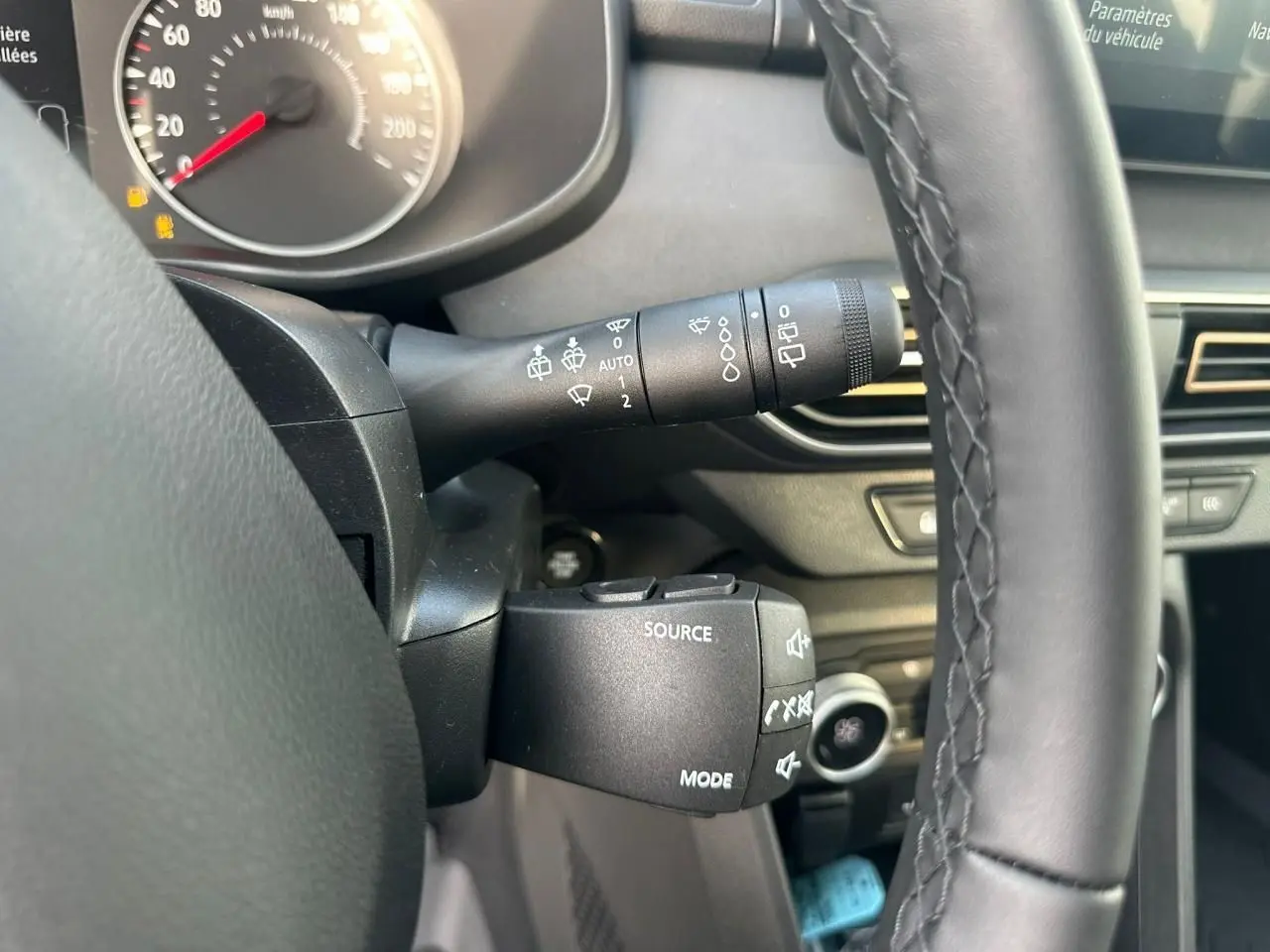 Gros plan sur la commande multimédia et le commodo d’essuie-glace côté gauche du volant d’une Dacia Sandero III Stepway.