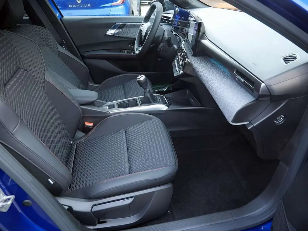 Vue intérieure côté conducteur de la Renault Clio VI 6 TCE 115 Techno Plus bleu iron, avec sièges tissu noir et console centrale moderne.