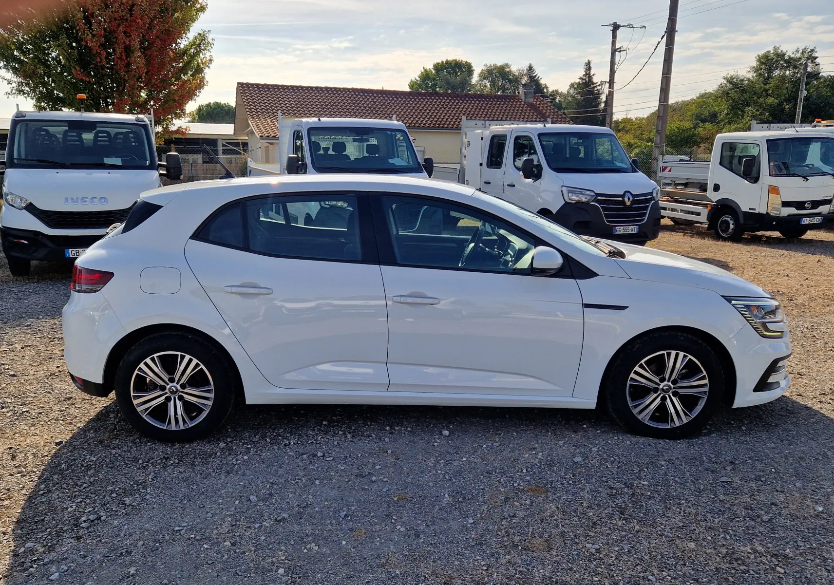 Renault Mégane 1.5 Blue dCi 115 Evolution blanche vue de profil côté gauche sur un terrain gravillonné.