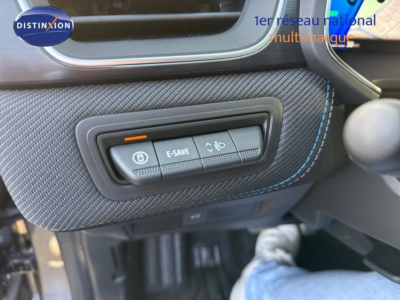 Détail intérieur montrant les boutons de commande E-SAVE et réglage des phares sur Renault Symbioz gris Cassiope, côté conducteur.