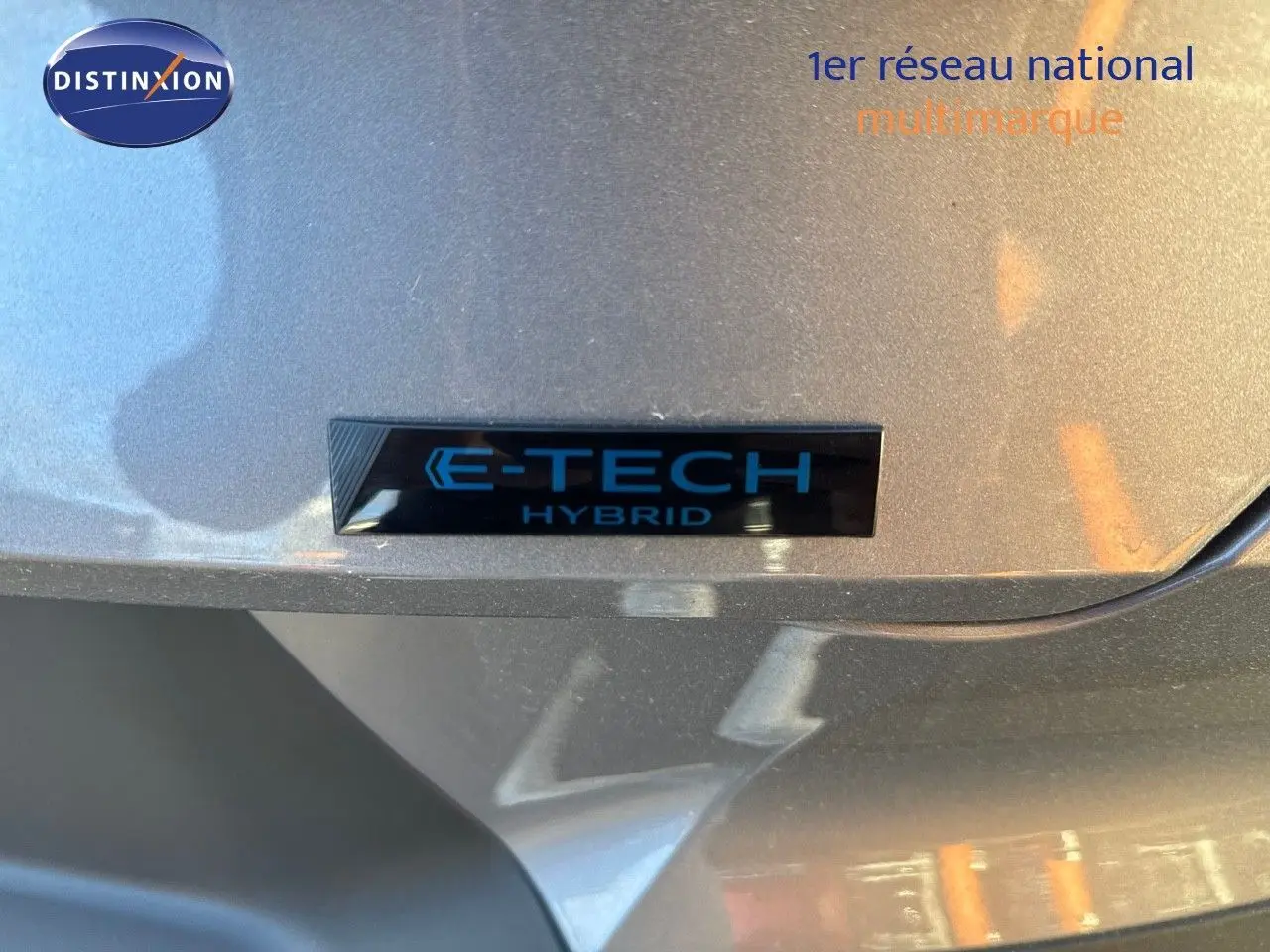 Gros plan sur l'emblème E-TECH Hybrid sur la partie arrière grise cassiope du Renault Symbioz 2024.