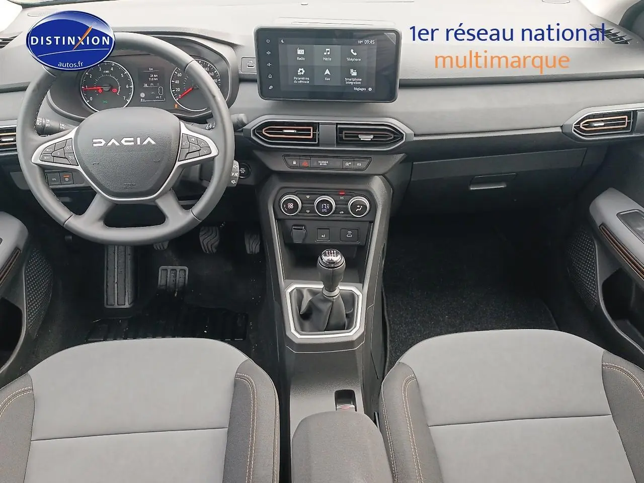 Intérieur de la Dacia Sandero 2025 vue de face, tableau de bord noir avec écran tactile et boîte manuelle.