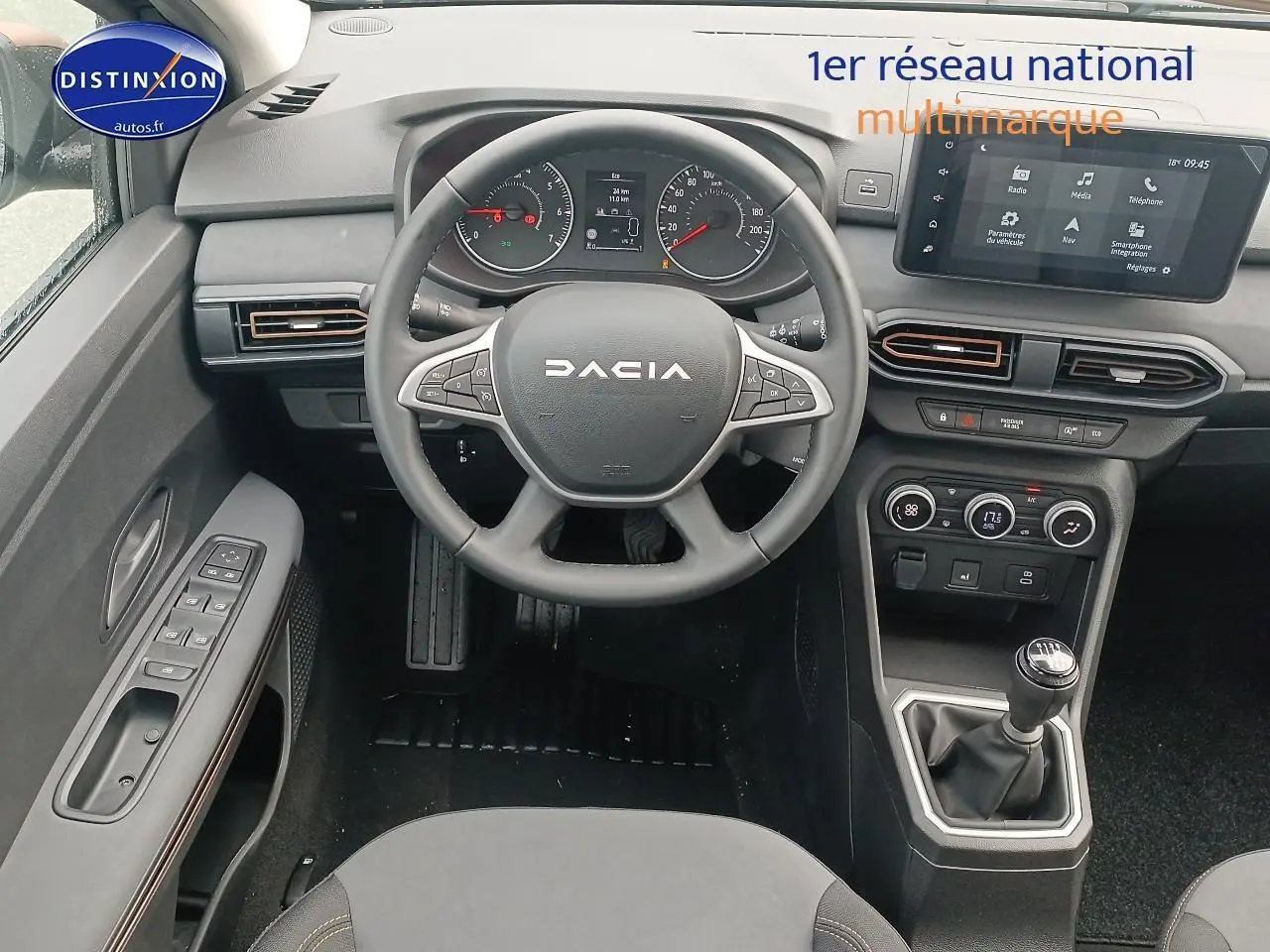 Intérieur de la Dacia Sandero 2025 vue du poste de conduite, volant DACIA, boîte manuelle et écran tactile central.