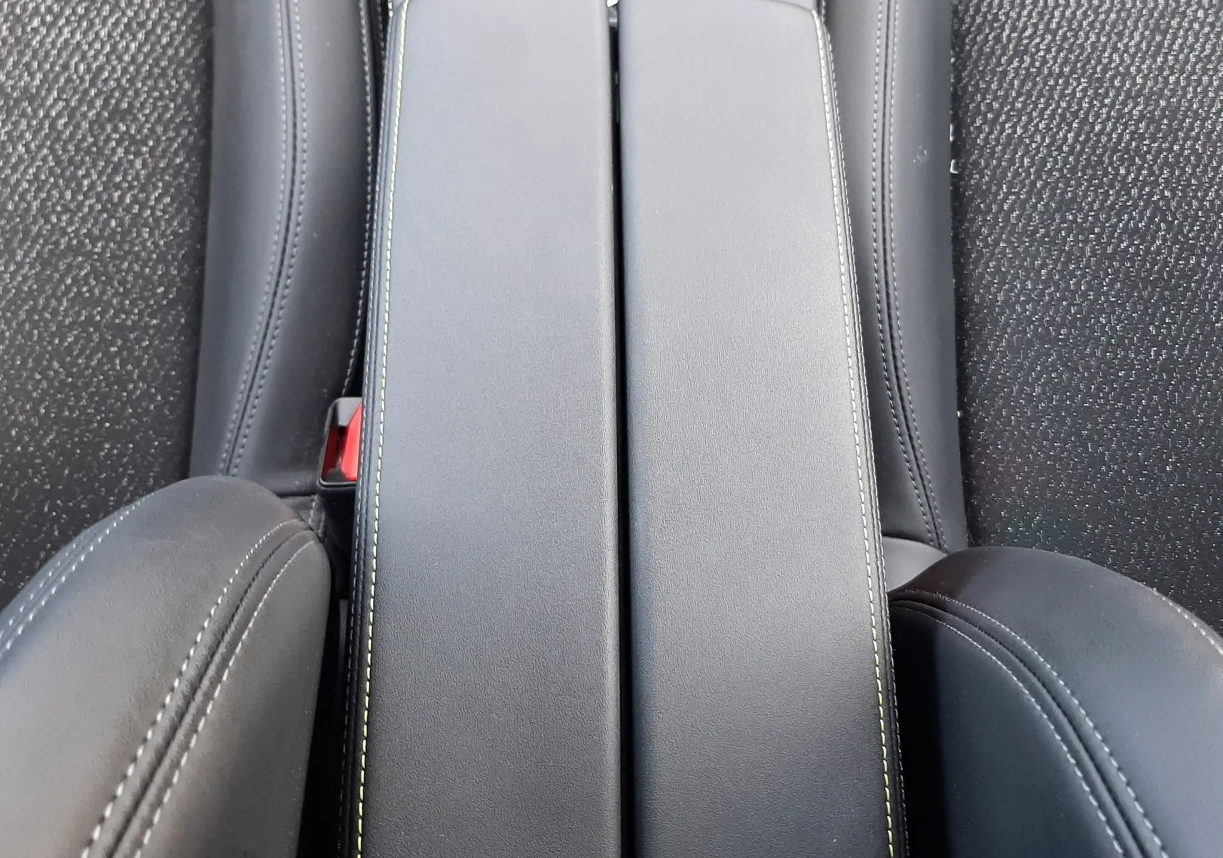 Gros plan sur l'accoudoir central noir avec surpiqûres contrastantes dans l'habitacle d'une Peugeot 308 SW.