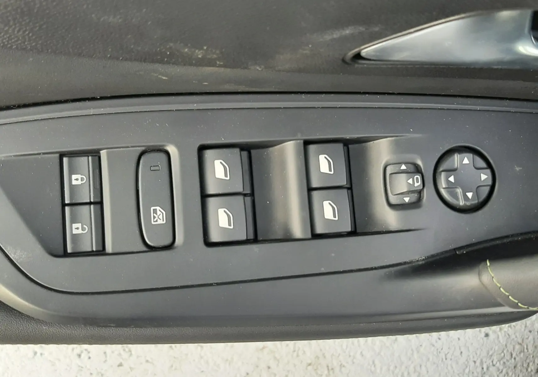 Vue rapprochée des commandes de lève-vitres et réglage des rétroviseurs côté gauche d’une Peugeot 308 SW blanche 2024.