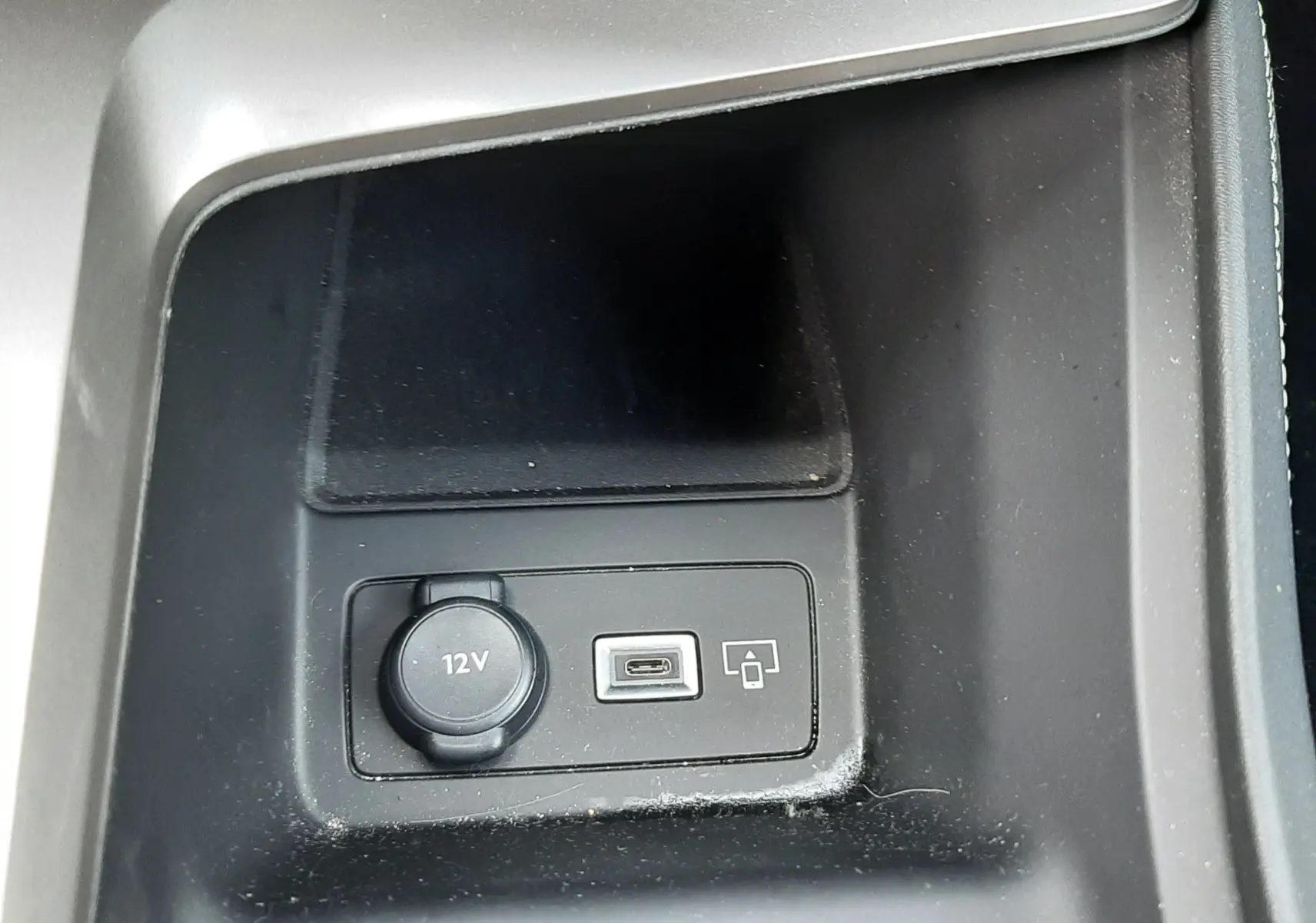 Gros plan sur la prise 12V et port USB dans la console centrale noire du Peugeot 308 SW 2024.
