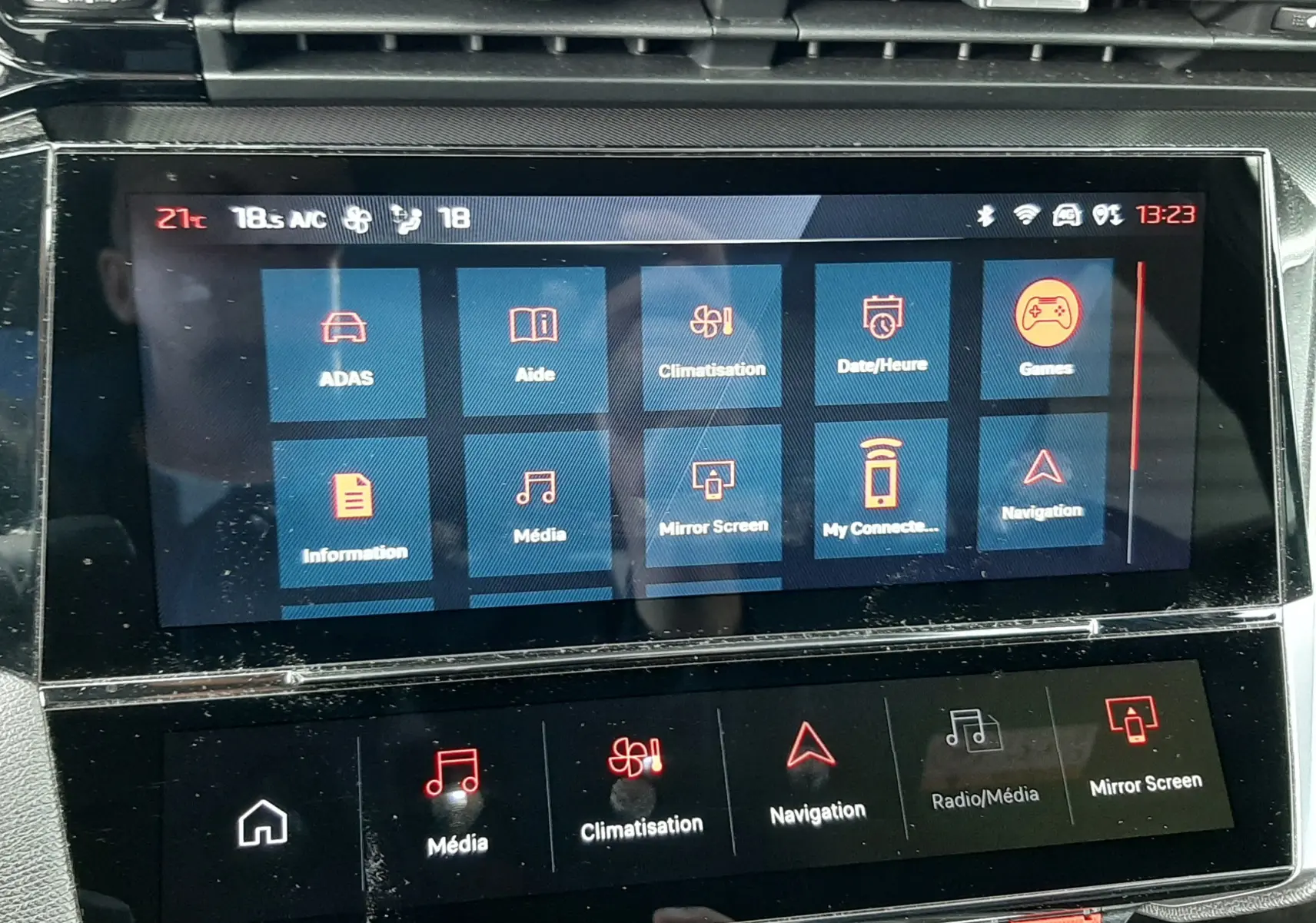 Écran tactile central de la Peugeot 308 SW blanc Okenite, affichant le menu multimédia et climatisation, vue frontale rapprochée.