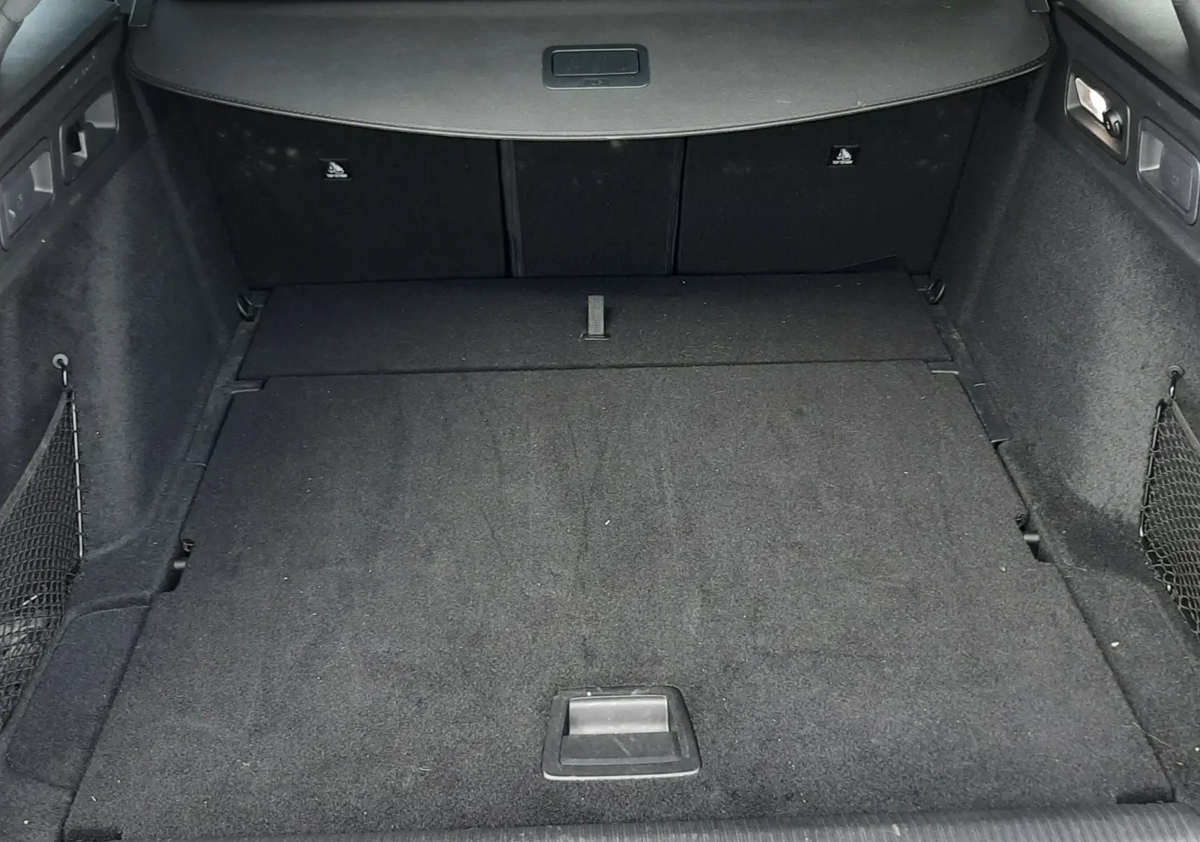 Vue intérieure du coffre spacieux et noir du Peugeot 308 SW 2024, avec banquette arrière et tablette cache-bagages visibles.