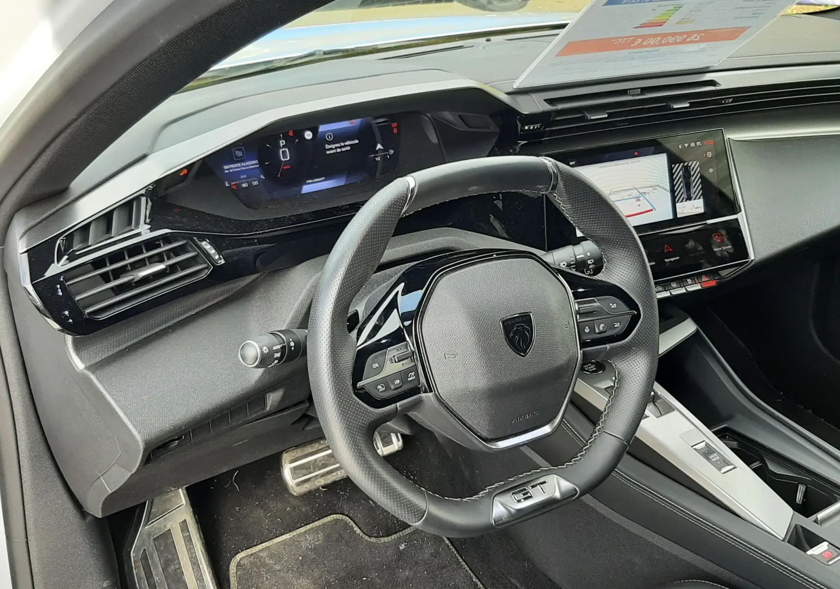 Vue intérieure côté conducteur du tableau de bord et volant noir de la Peugeot 308 SW GT 2024 blanche.