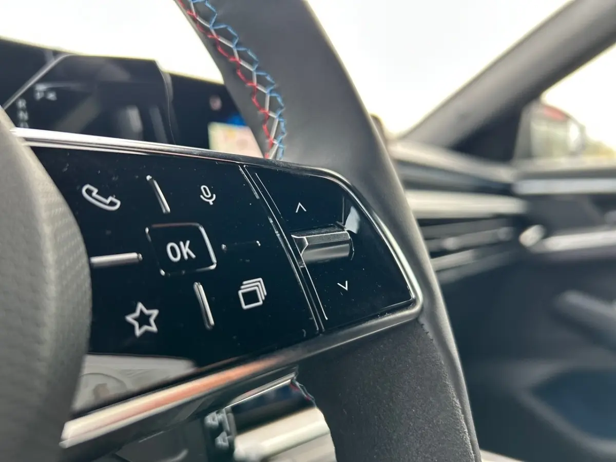 Gros plan sur les commandes du volant noir avec surpiqûres tricolores du Renault Rafale esprit Alpine hybride 2025.