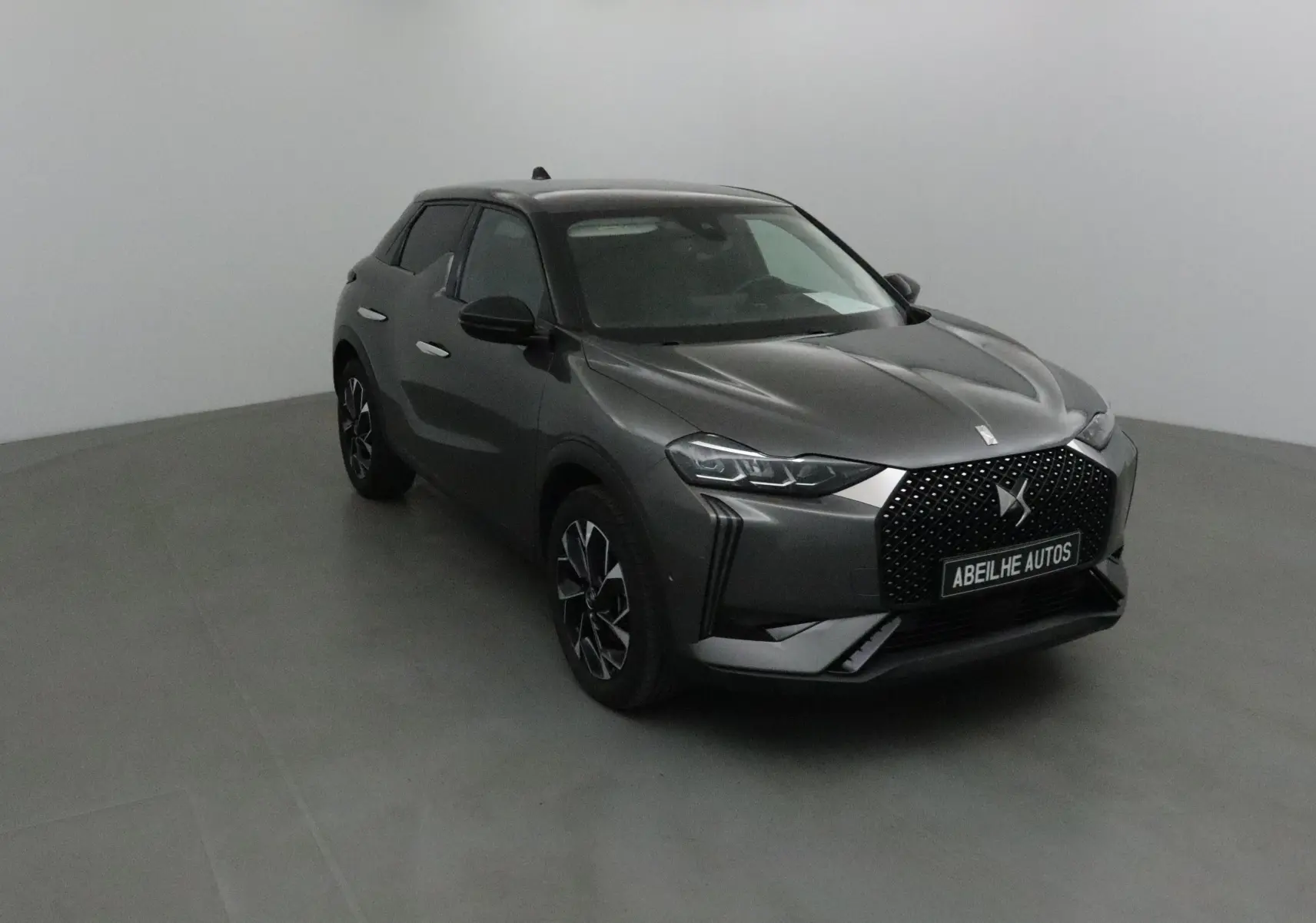 DS3 Crossback gris platinium en 3/4 avant droit, avec calandre distinctive et jantes stylisées visibles.