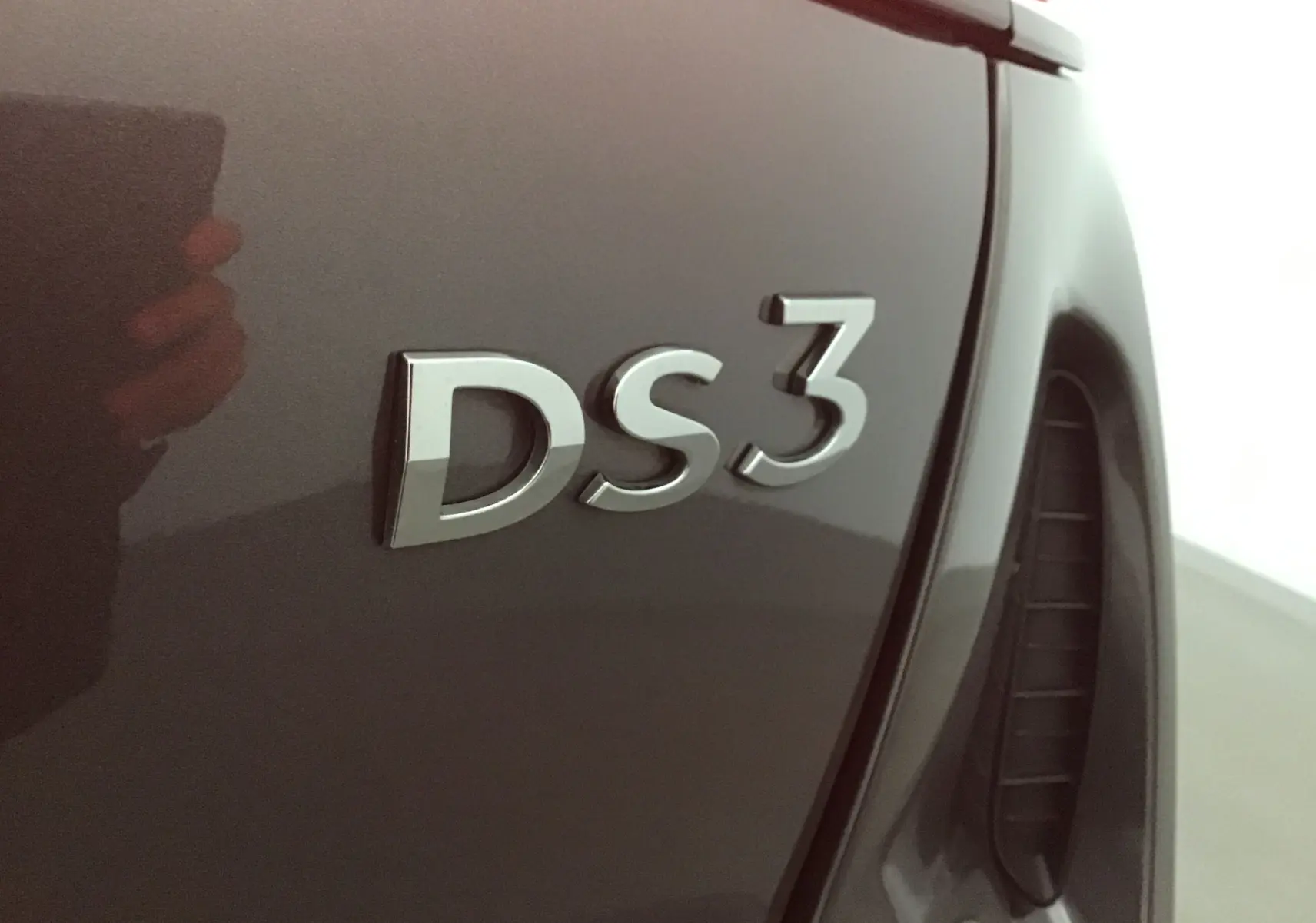 Gros plan sur l’inscription DS3 en relief sur la carrosserie gris platinium du DS3 Crossback 2024 côté arrière droit.