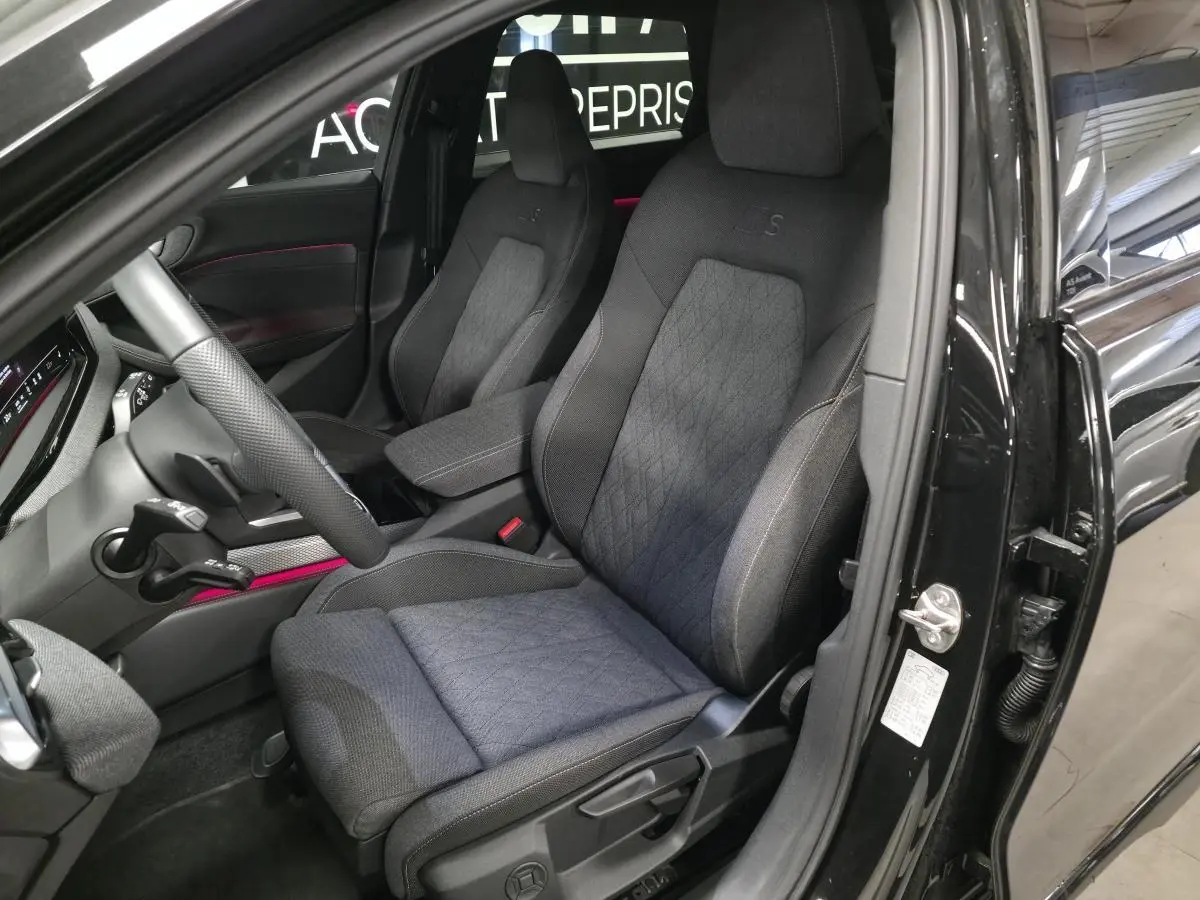 Vue intérieure côté conducteur de l'Audi A5 Avant noire 2025, sièges sport S en tissu avec surpiqûres beige cardamome.