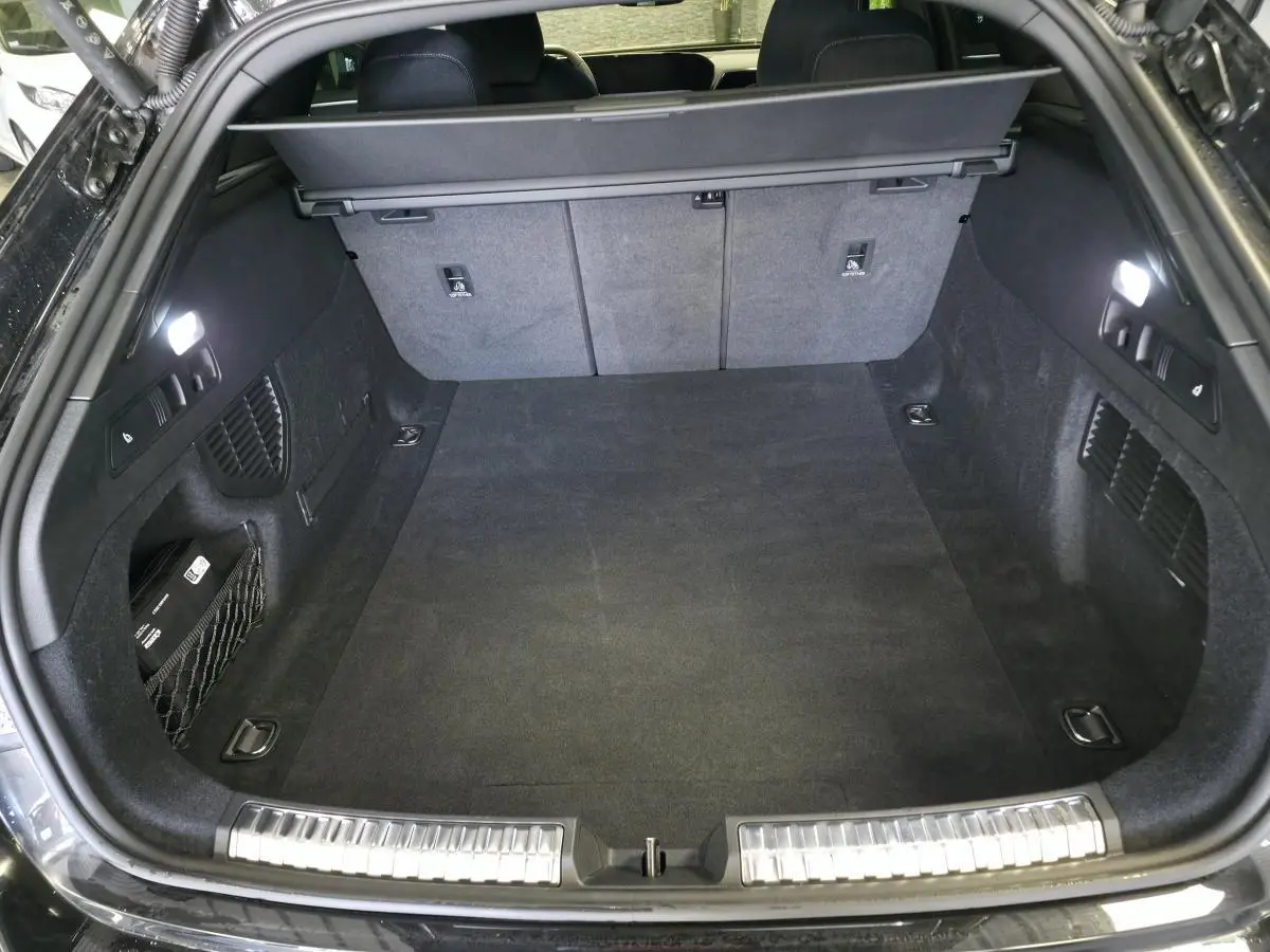 Coffre ouvert vu de l'arrière d'un break Audi A5 noir, avec tapis et éclairage intérieur LED.