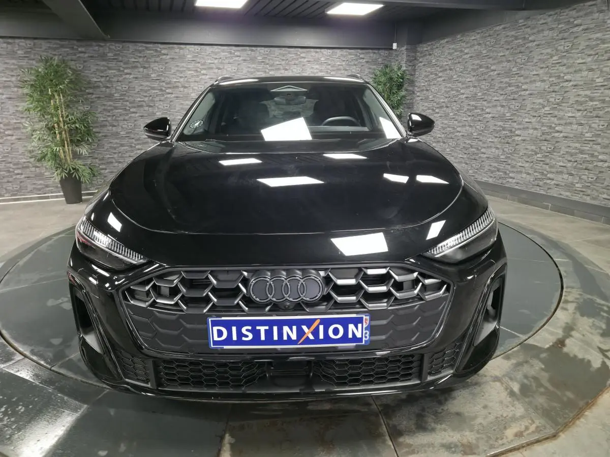 Vue frontale d'une Audi A5 Avant S line noire, mettant en valeur sa calandre hexagonale et ses phares LED fins.