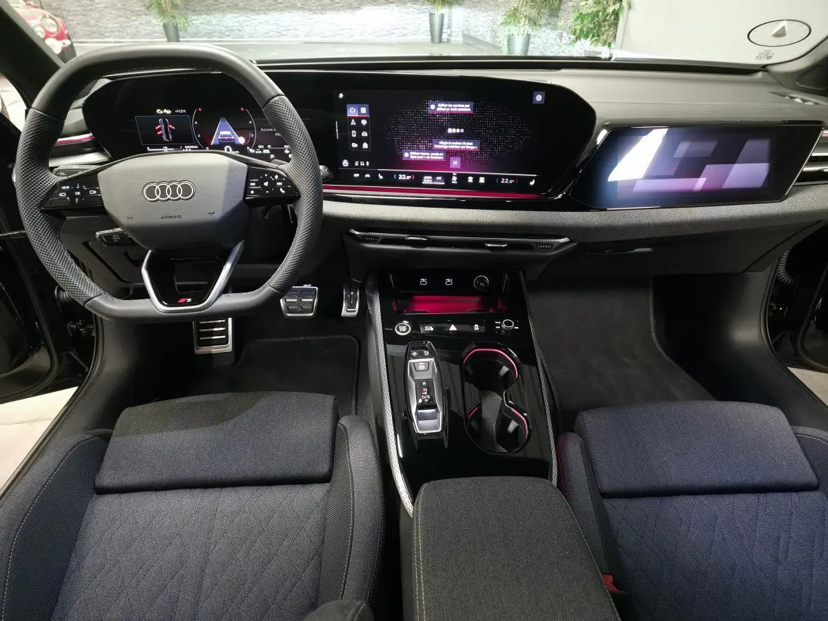 Vue intérieure avant de l'Audi A5 Avant 2025, tableau de bord noir avec écran digital et volant sport multifonction S line.
