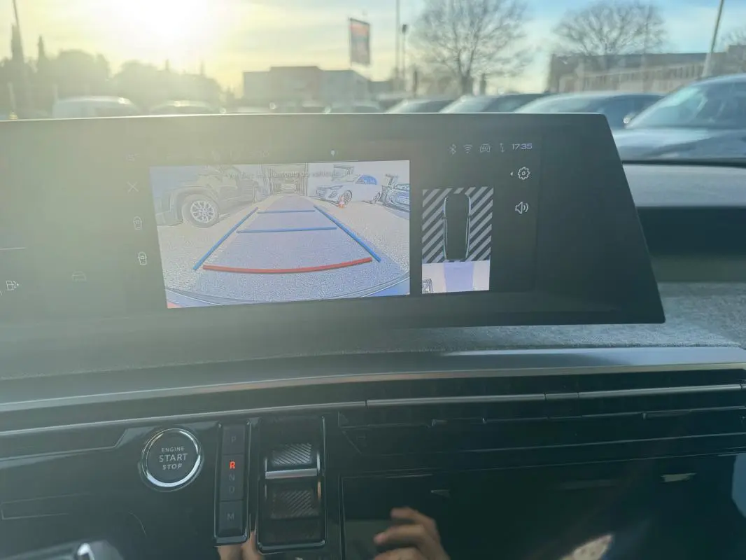 Vue intérieure du tableau de bord du Peugeot 3008 Hybrid gris 2025, écran affichant la caméra de recul et commandes modernes.