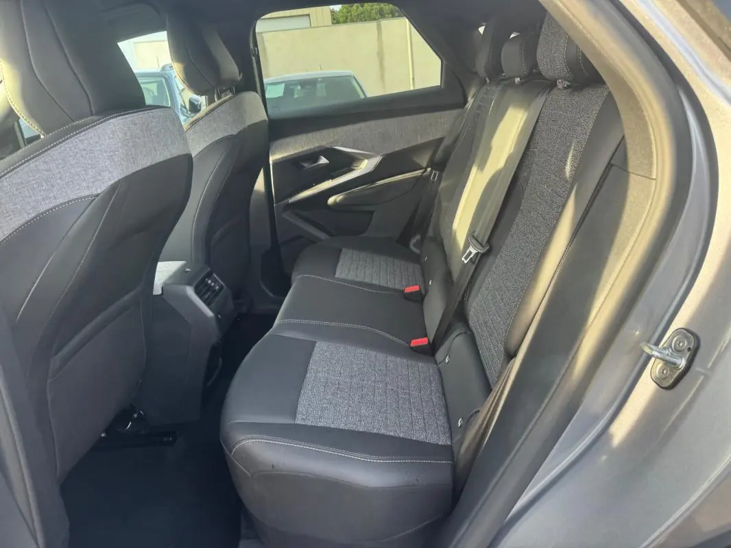 Vue côté droit de l'intérieur arrière gris du Peugeot 3008 Hybrid 145 e-DCS6 Allure avec sièges tissu et cuir bicolores.