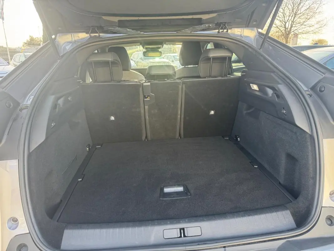 Coffre ouvert vu de l’arrière d’un Peugeot 3008 gris 2025, montrant l’espace de chargement et les sièges arrière rabattus.