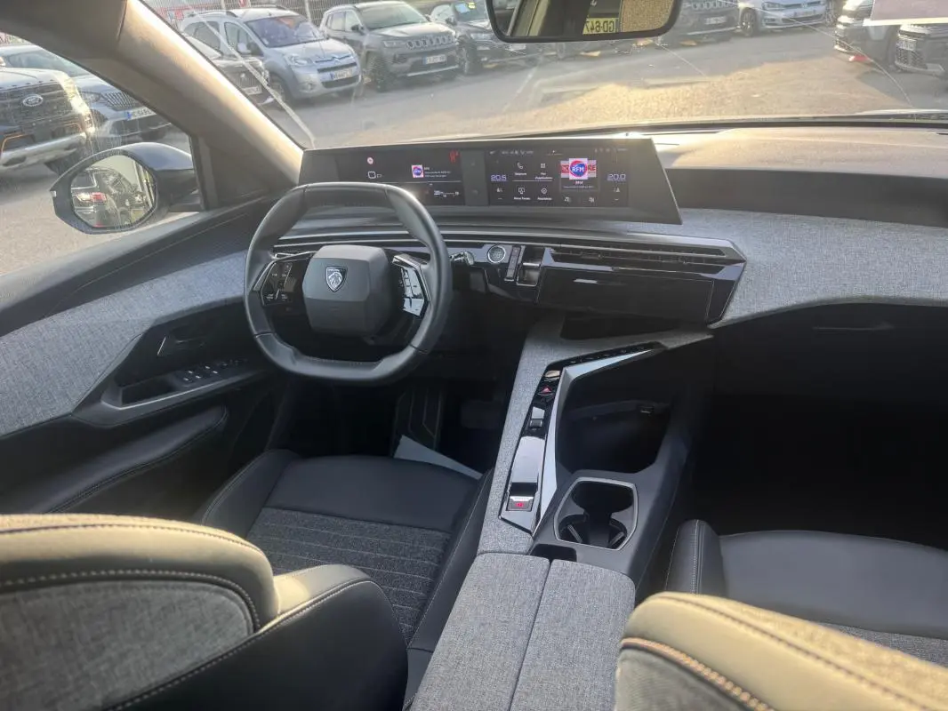 Vue intérieure avant du Peugeot 3008 Hybrid 145 Allure 2025, tableau de bord moderne avec cockpit numérique et sellerie grise.