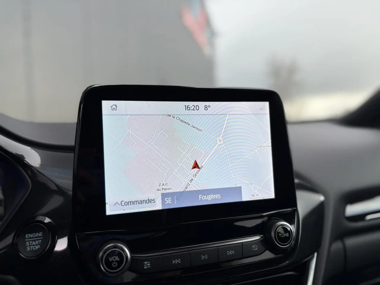 Écran tactile GPS au centre du tableau de bord du Ford Puma gris, avec commandes audio et bouton start/stop visibles.