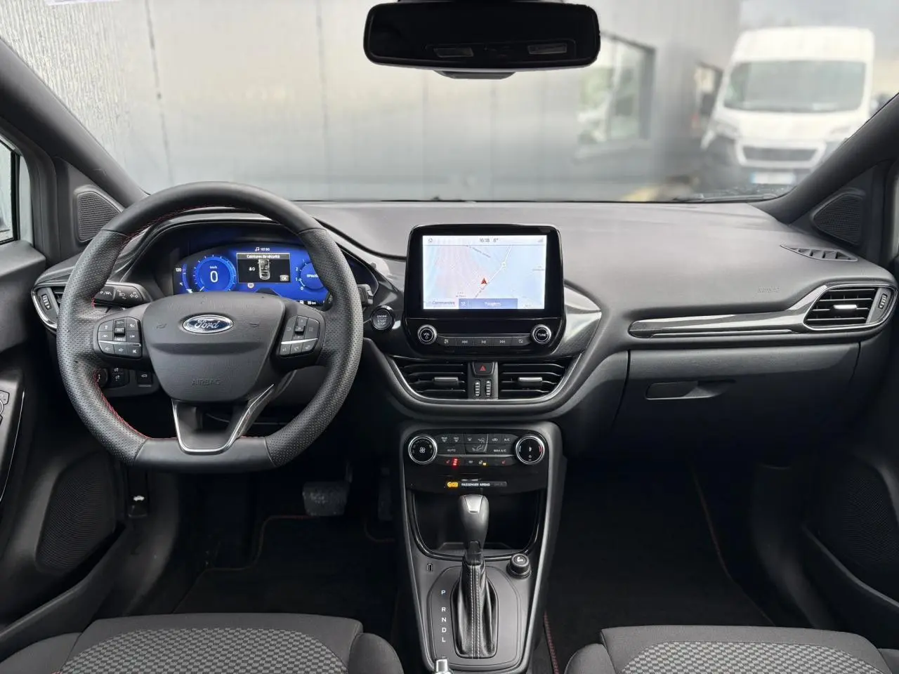 Vue intérieure frontale du tableau de bord et volant ST-Line perforé de la Ford Puma 2024, écran tactile GPS allumé.