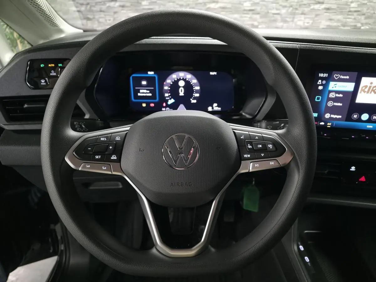 Vue rapprochée du volant noir multifonction du Volkswagen Caddy 2024 avec tableau de bord digital et écran tactile.