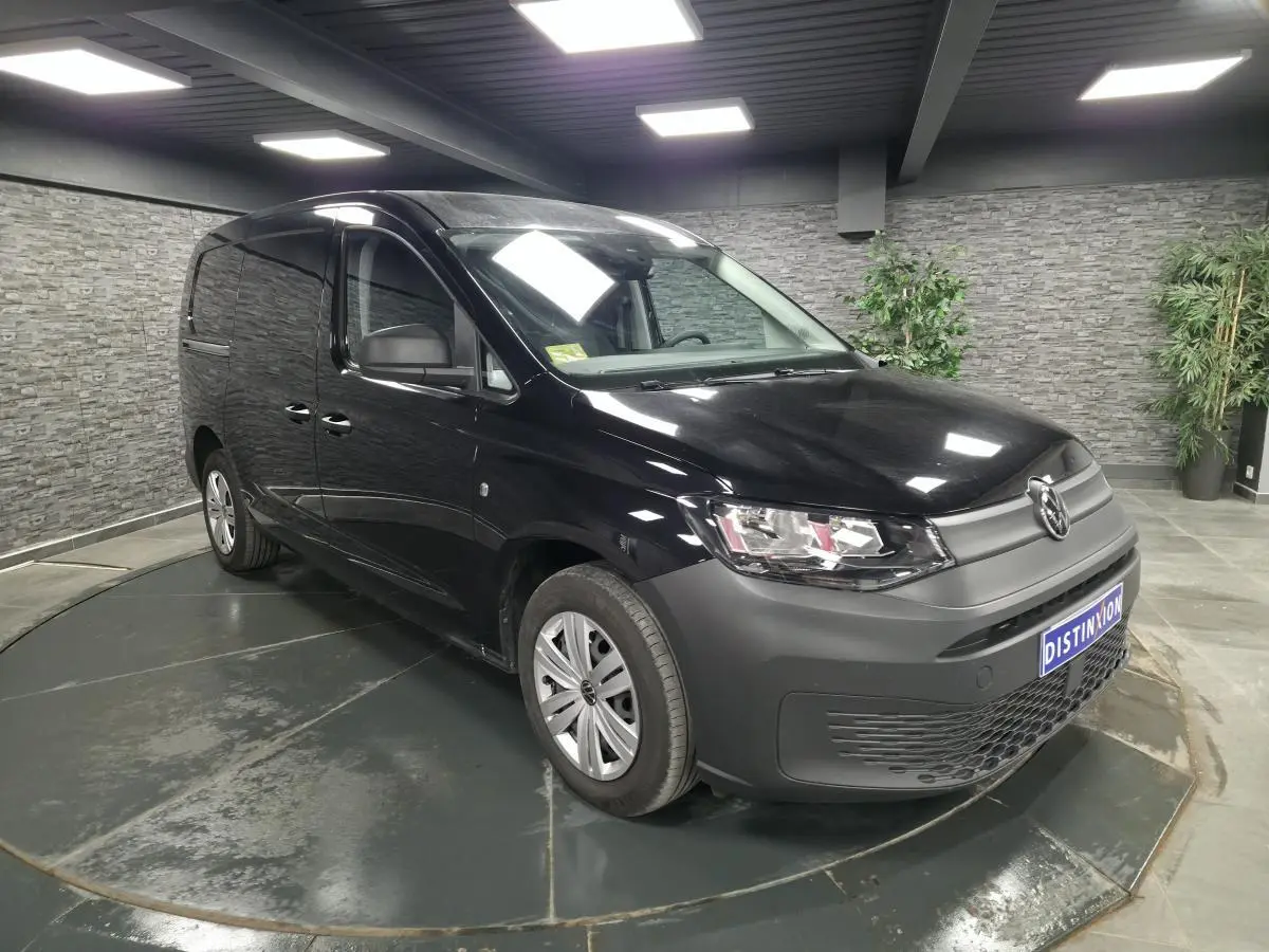 Volkswagen Caddy Cargo noir vue 3/4 avant droit en intérieur avec pare-chocs et jantes noires.
