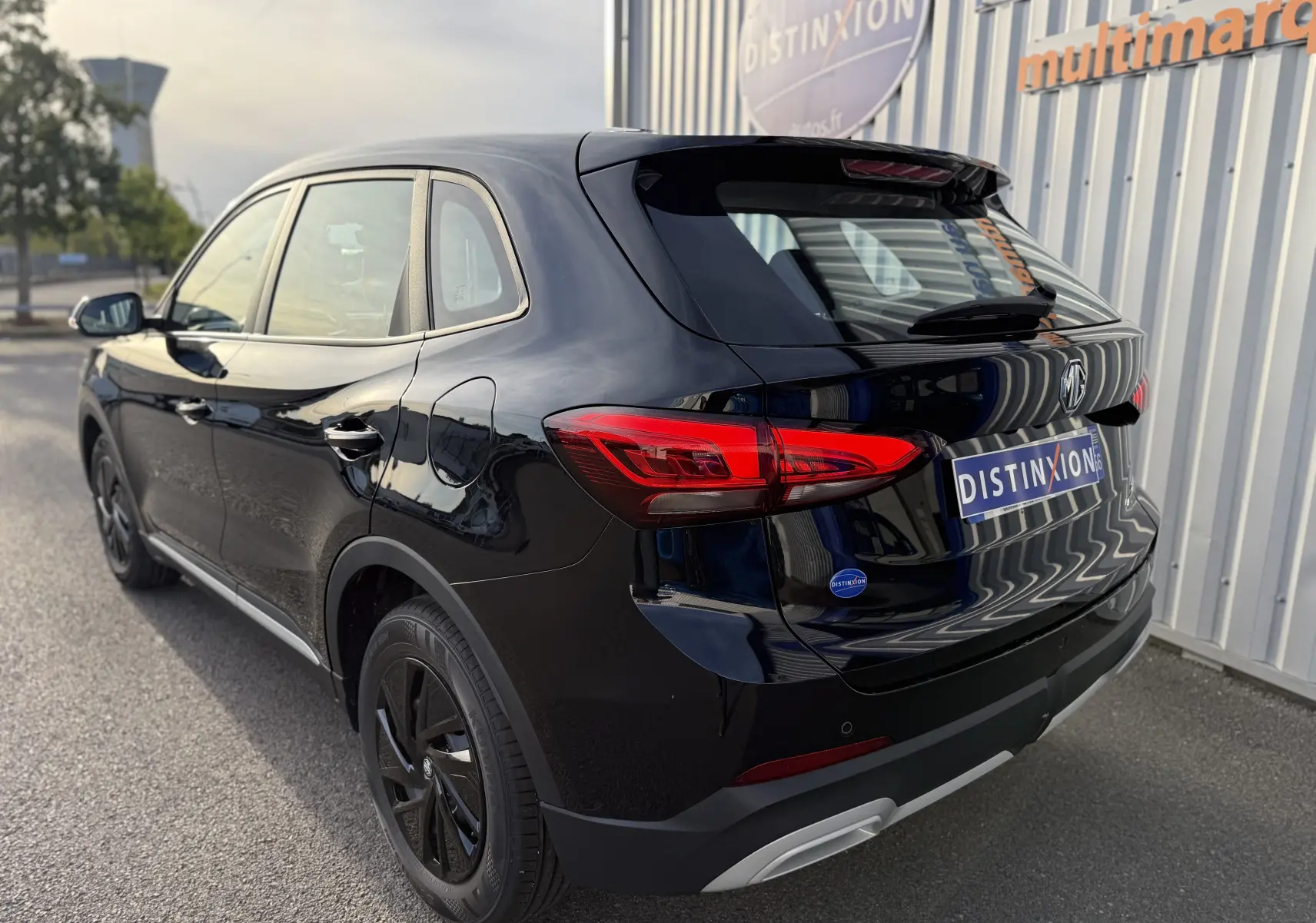 Vue 3/4 arrière droite d’un MG MOTOR ZS Hybrid 197 Standard noir brillant, avec feux arrière LED et jantes noires.