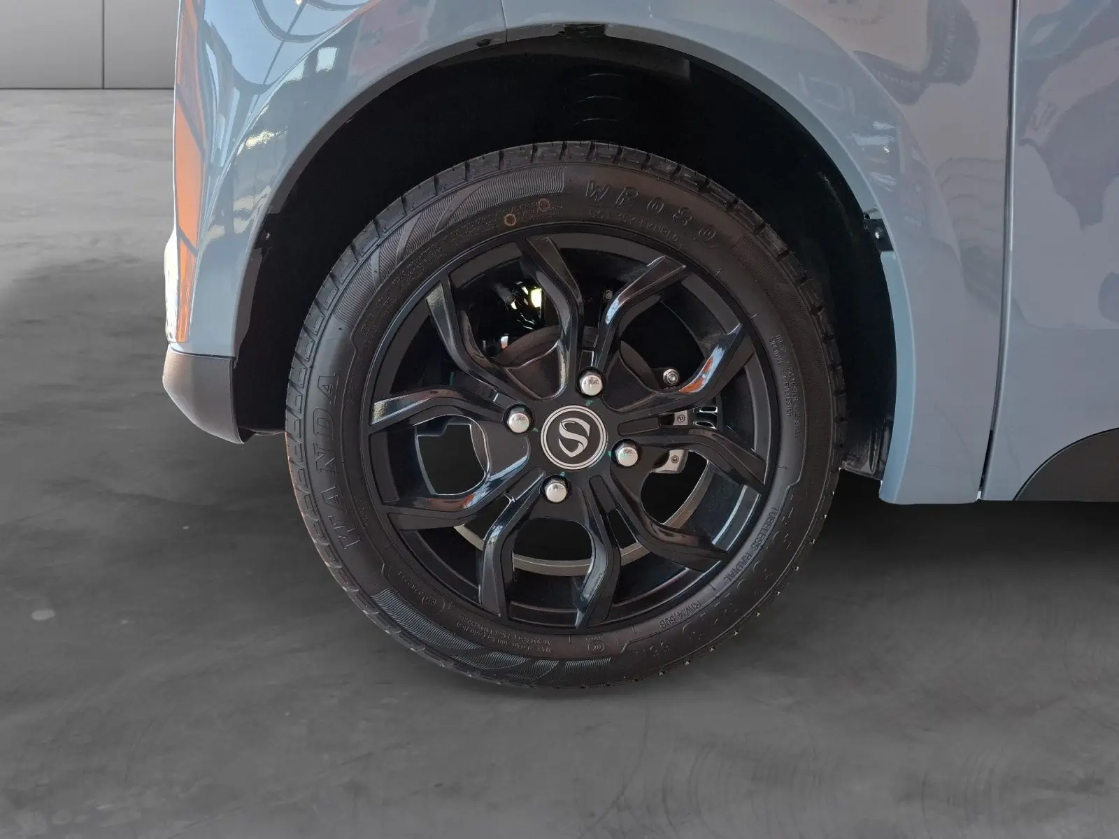 Gros plan sur la roue avant droite noire avec jante en alliage du SIMPLICI S1 gris perle au toit noir.