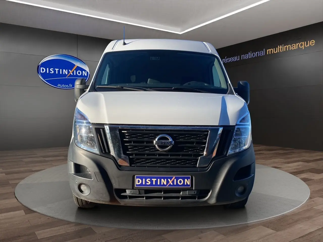 Vue frontale d’un utilitaire Nissan Interstar blanc avec calandre noire et pare-chocs avant noir mat dans un showroom.