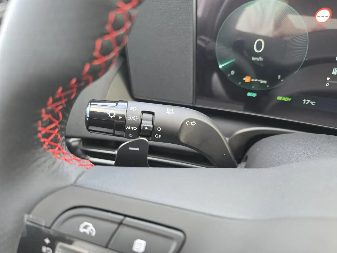 Gros plan sur la manette des feux et clignotants du Hyundai Tucson N Line 2025, volant cuir noir à surpiqûres rouges visible.