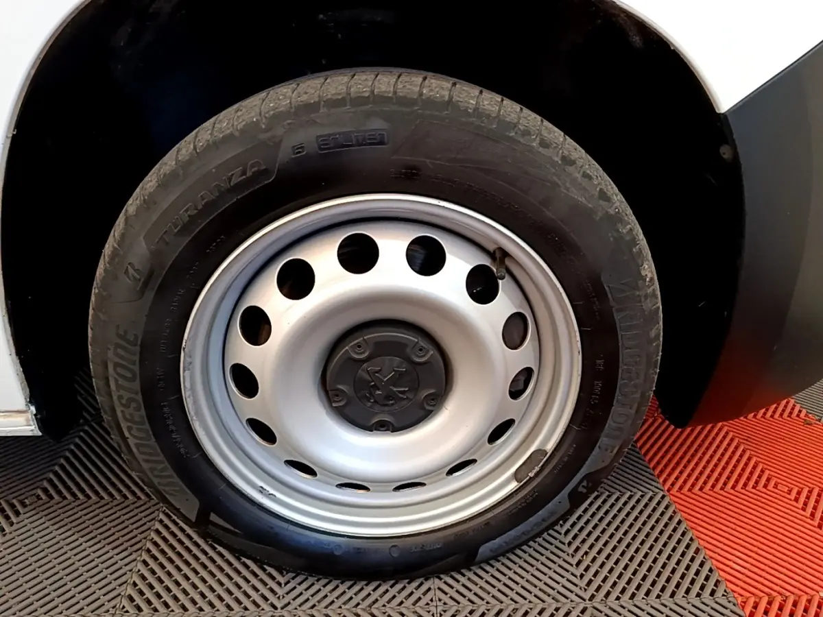Gros plan sur la roue avant droite en jante acier du Peugeot Partner blanc, avec pneu Bridgestone.