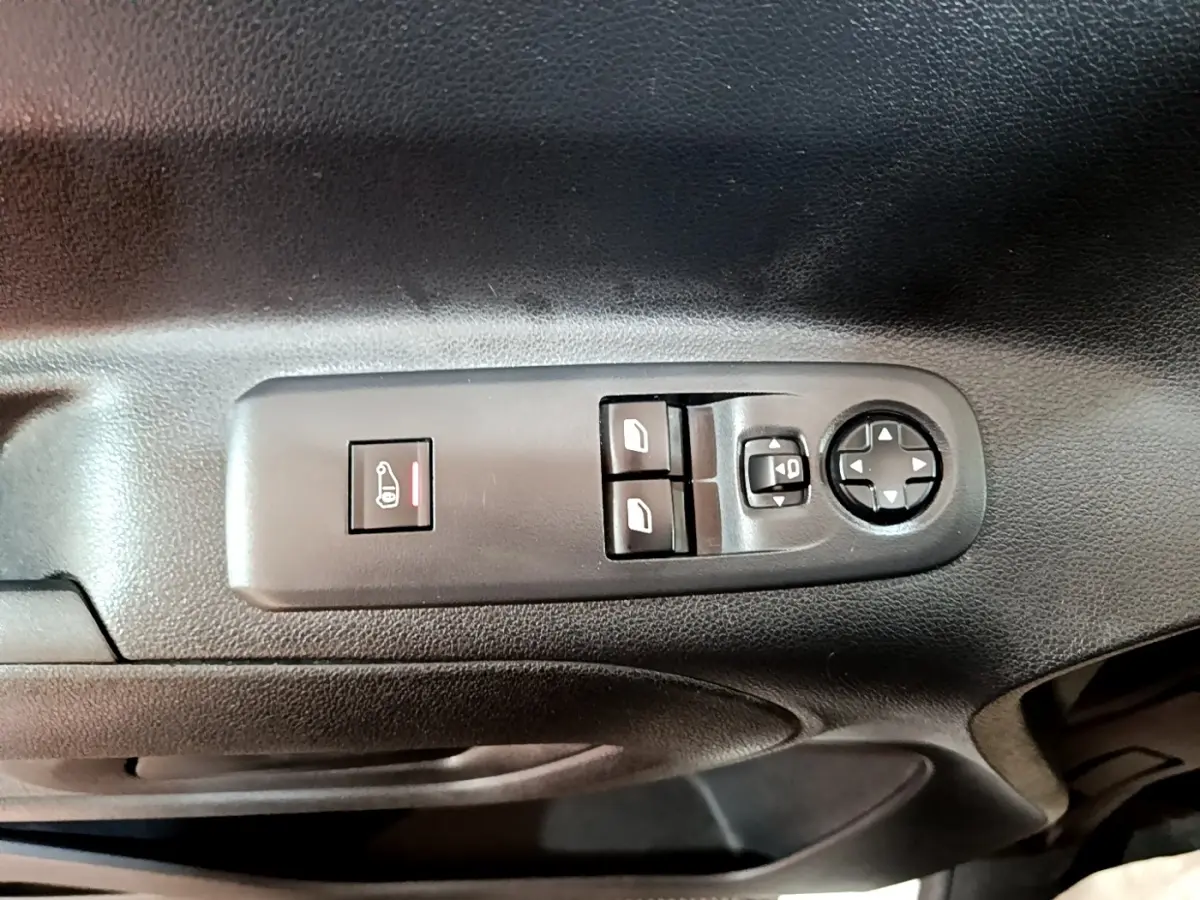 Gros plan sur les commandes de lève-vitres et réglage des rétroviseurs sur la porte intérieure noire d’un Peugeot Partner blanc.