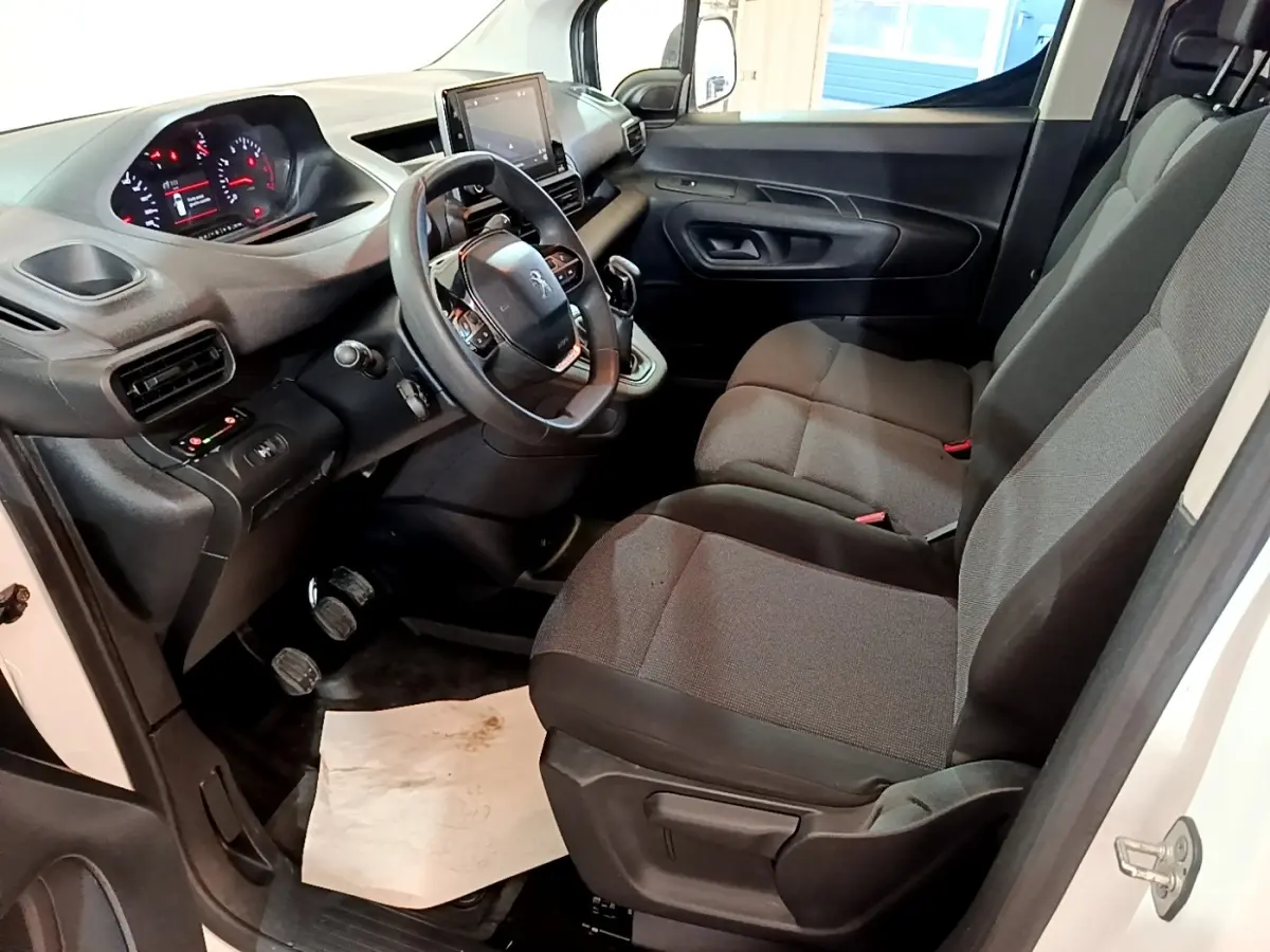 Intérieur avant droit du Peugeot Partner blanc 2021, montrant sièges tissu gris et tableau de bord avec écran tactile.