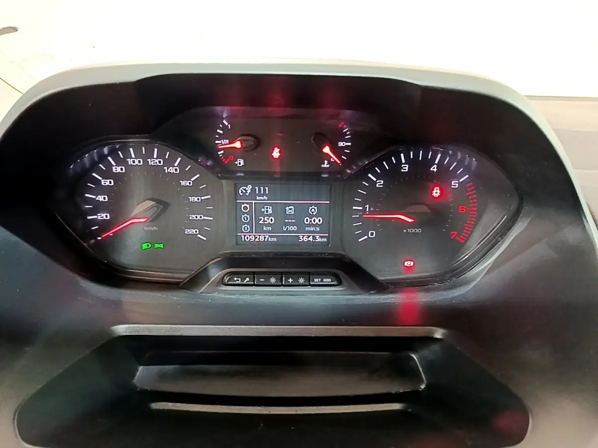 Vue rapprochée du tableau de bord numérique du Peugeot Partner 2021, affichant vitesse, compte-tours et informations de conduite.