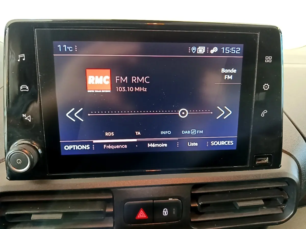 Écran tactile central du tableau de bord du Peugeot Partner blanc, affichant la radio FM RMC à 103,10 MHz.
