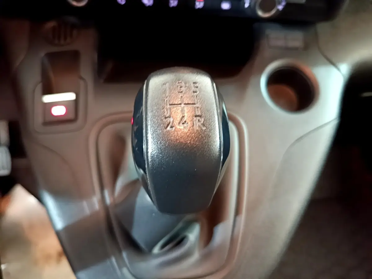 Gros plan sur le levier de vitesses manuel noir du Peugeot Partner 2021, avec console centrale beige en arrière-plan.