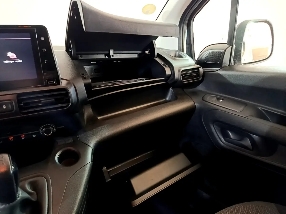 Vue intérieure côté passager du Peugeot Partner 2021, tableau de bord noir avec boîte à gants ouverte et écran tactile visible.