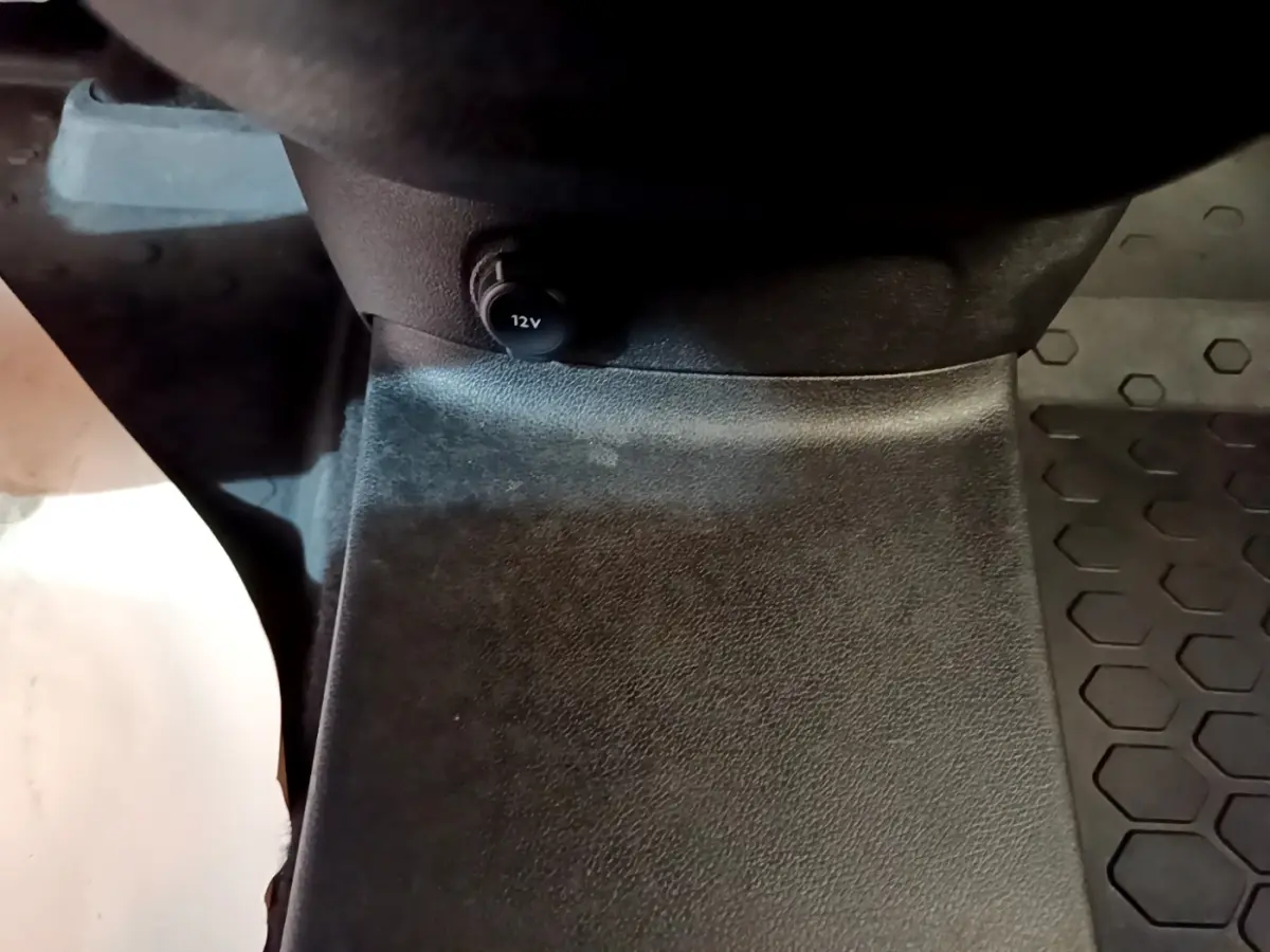 Gros plan sur la prise 12V noire située au bas de la console centrale intérieure du Peugeot Partner blanc.