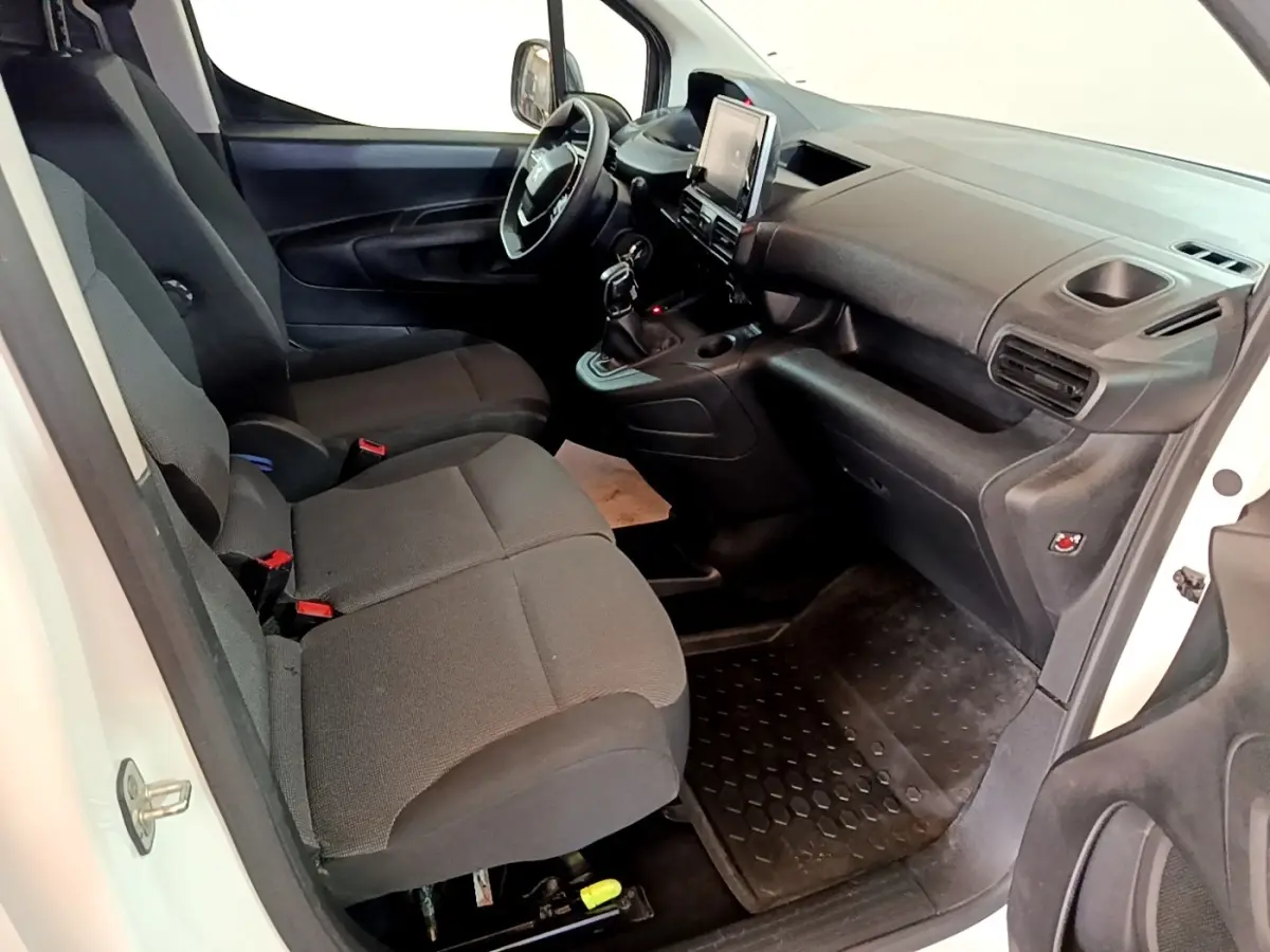 Vue intérieure côté conducteur du Peugeot Partner blanc 2021, montrant sièges noirs et tableau de bord avec écran tactile central.