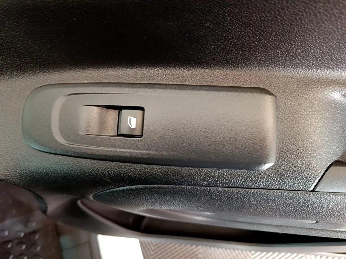 Gros plan sur le bouton de commande de la vitre électrique côté conducteur du Peugeot Partner blanc de 2021.