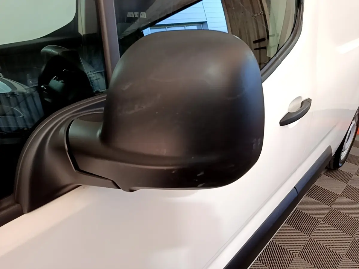 Vue rapprochée du rétroviseur noir côté conducteur sur la porte blanche d’un Peugeot Partner 2021.