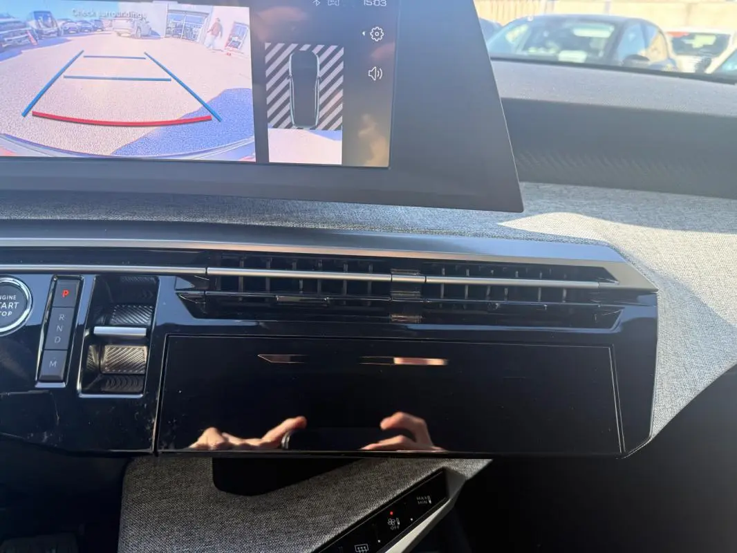 Vue rapprochée du tableau de bord noir brillant du Peugeot 3008 Hybrid 145 Allure avec écran de caméra de recul allumé.