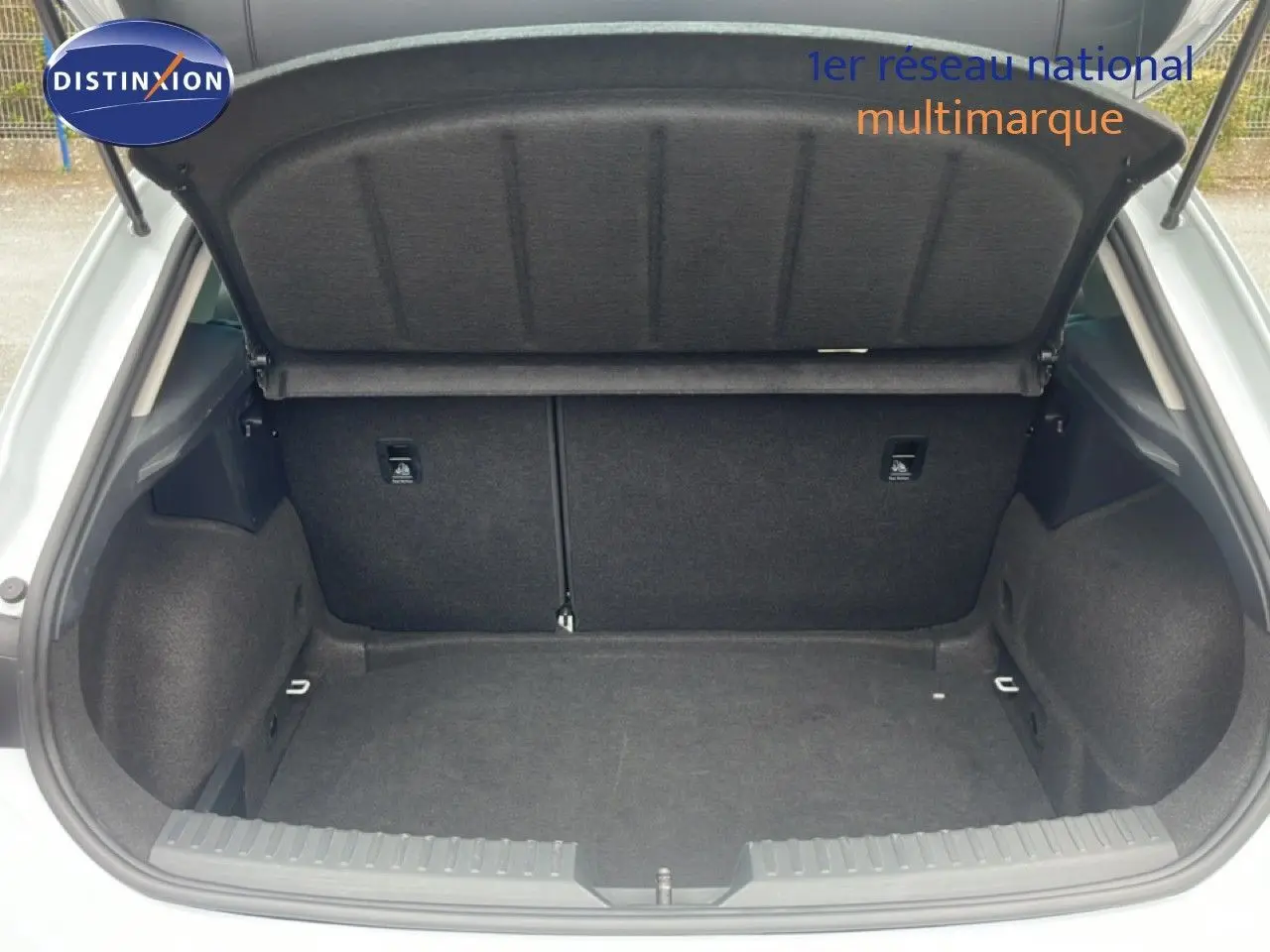 Coffre ouvert vu de l'arrière d'une SEAT LEON blanc neige métal, montrant un espace de chargement propre et spacieux.