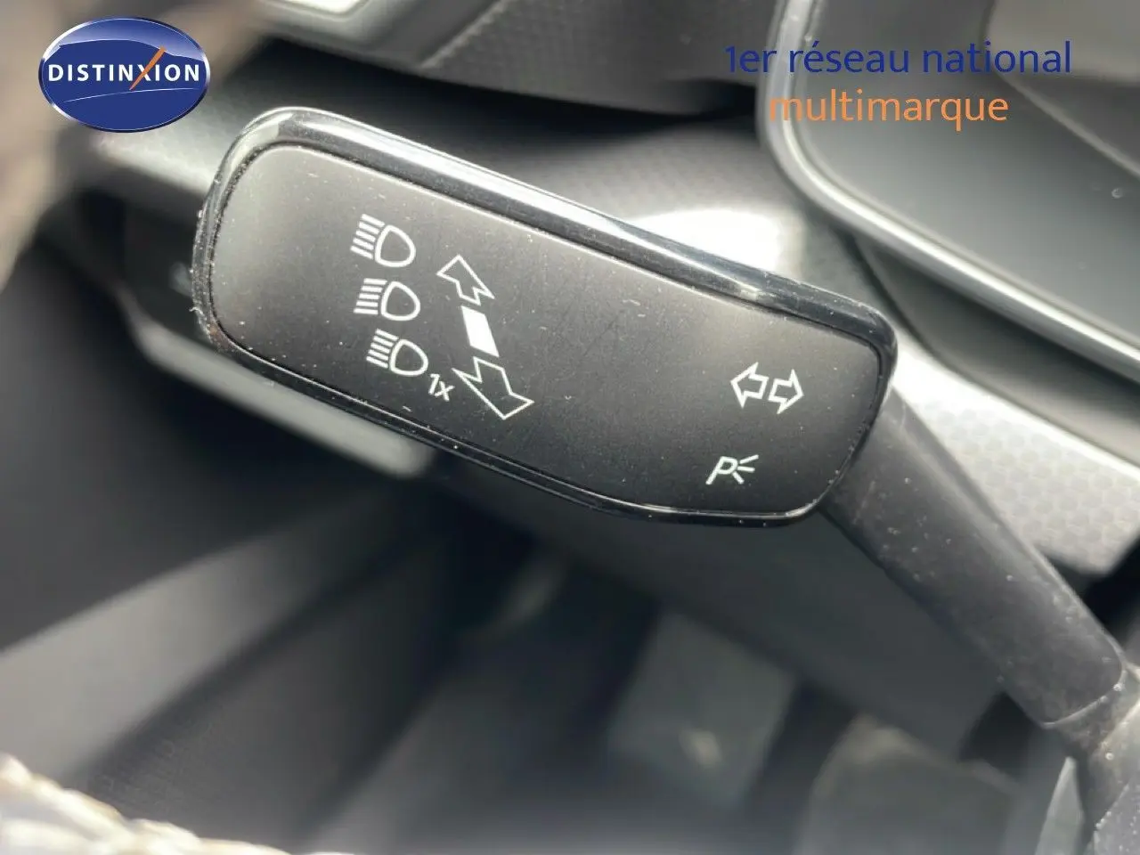 Gros plan sur la commande de clignotants et feux d’un SEAT Leon blanc neige métal 2025, intérieur gris noir.