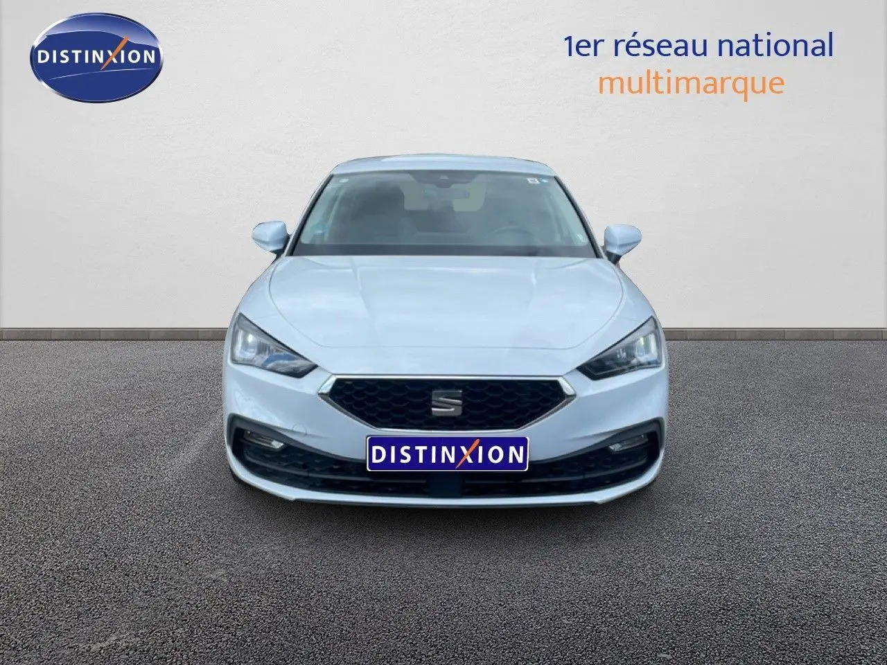 Vue frontale d'une SEAT Leon 2.0 TDI blanche neige métal avec calandre hexagonale et phares LED distinctifs.