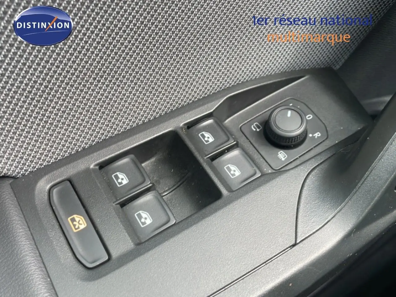 Gros plan sur les commandes des vitres électriques et rétroviseurs côté gauche d'une SEAT LEON blanc neige métal.