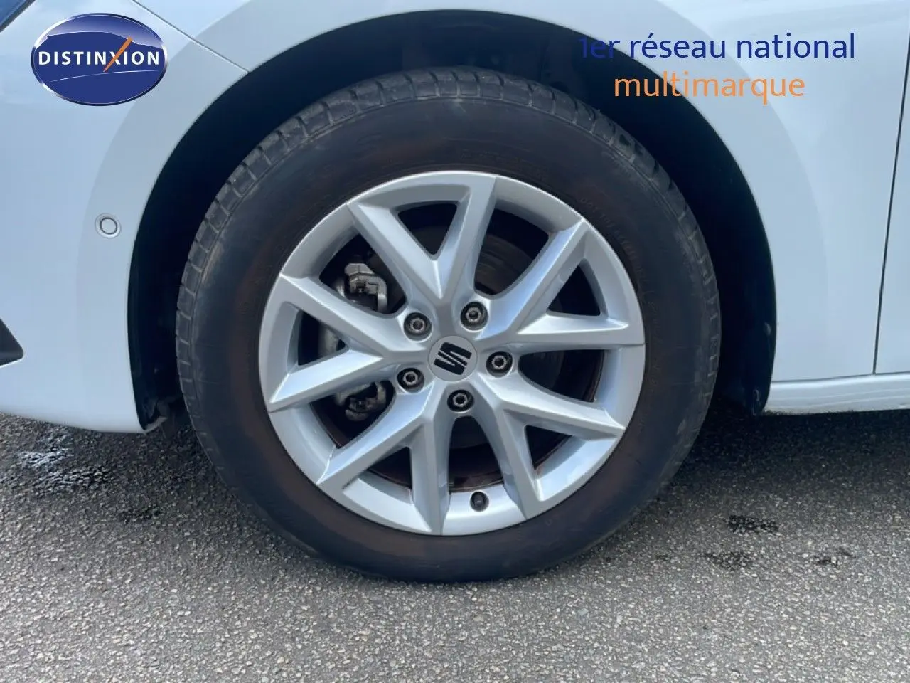 Gros plan sur la roue avant droite d’une SEAT LEON blanc neige métal avec jante alliage à 5 doubles branches.